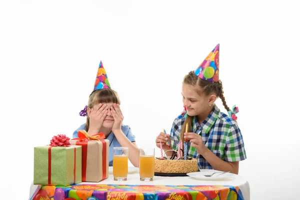 Jedna Dziewczyna Zakryła Oczy Rękami Druga Wkłada Zapałki Tortu Urodzinowego — Zdjęcie stockowe