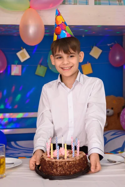 生日那天 一个男孩拿着蛋糕站在桌旁 — 图库照片