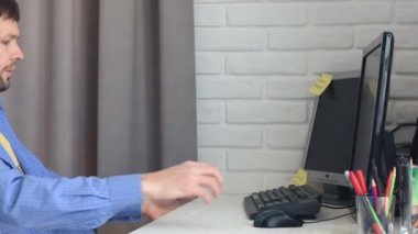 Genç adam bir bilgisayarla bir iş yerinde çömeldi ve çalışmaya başladı.