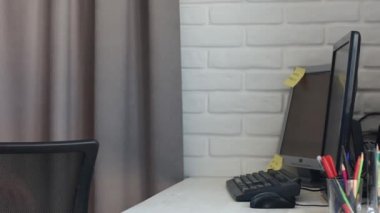 Çalışma koltuğuna çömelmiş telefonu olan genç bir adam.