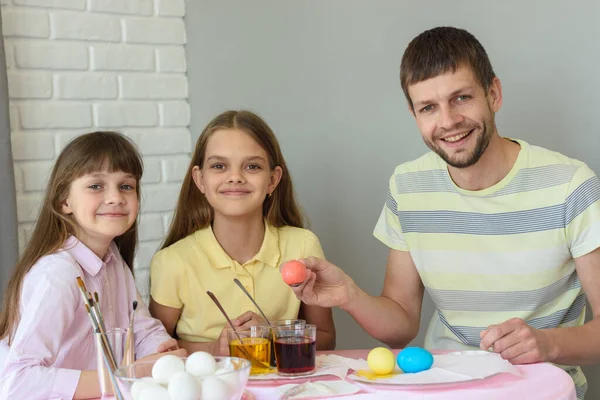 快乐的一家人在桌旁画着复活节彩蛋 高兴地看着镜框 — 图库照片