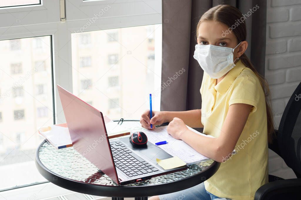 Girl in self-isolation studying online sitting by the window at home