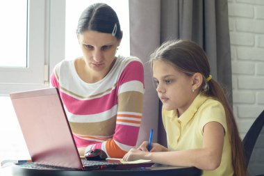 Anne ve kızı ev ödevlerini internet üzerinden öğrenerek çözüyor.