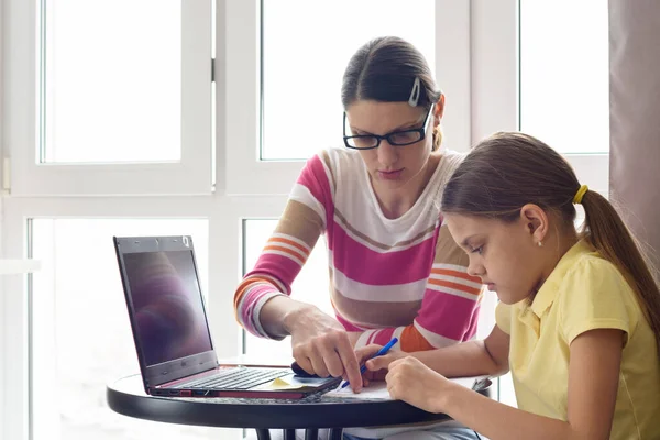 家庭教師は子供がテーブルに座ってコンピュータを使うことを教えています — ストック写真
