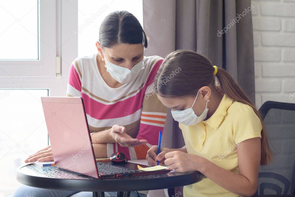 The girl explains to the girl how to solve the problem correctly, in self-isolation mode in medical masks