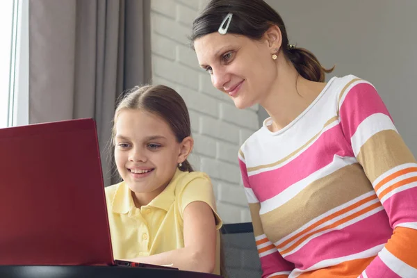 快乐的女孩和女孩正坐在桌旁 看着笔记本电脑的屏幕 — 图库照片