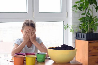 Evde kendini izole etmiş bir kız çömleğe tohum ekiyor.