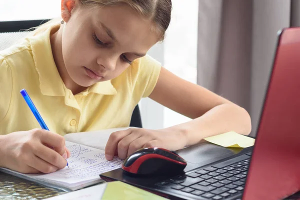 ノートにノートを書きながら遠隔で勉強する少女の閉鎖 — ストック写真