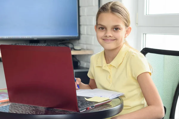 幸せな女の子はノートパソコンの前に座って遠隔で勉強する — ストック写真