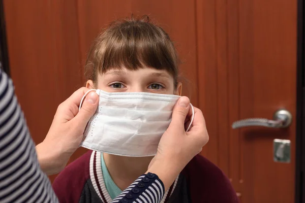Dziewczyna Zakłada Maskę Medyczną Przed Wyjściem Domu — Zdjęcie stockowe