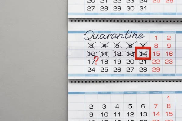 Calendar on a white wall with the inscription quarantine and crossed out days of the week