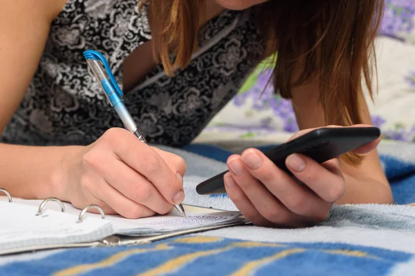 Girl Writes Information Smartphone Screen Notebook — Stock Photo, Image