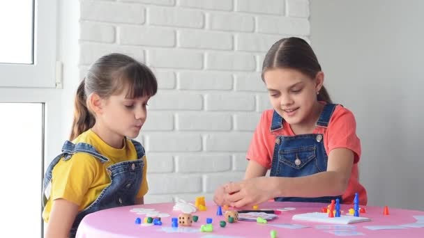 テーブルに座っている間に家庭用ボードゲームで二人の女の子 — ストック動画