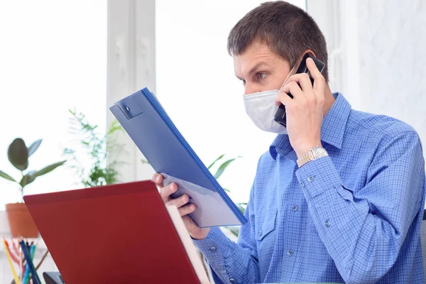 Человек Медицинской Маске Лице Читает Документ Офисе Разговаривает Телефону — стоковое фото