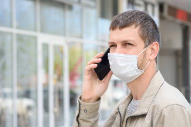 Mağazanın arka planında cep telefonu olan maskeli bir adamın portresi