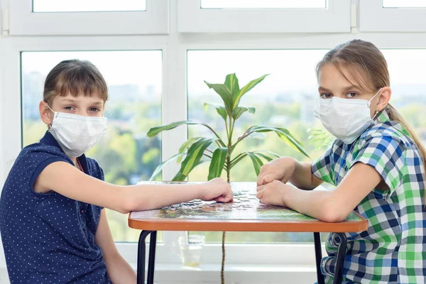 Twee Vriendinnen Met Medische Maskers Spelen Puzzels Kijken Het Frame — Stockfoto