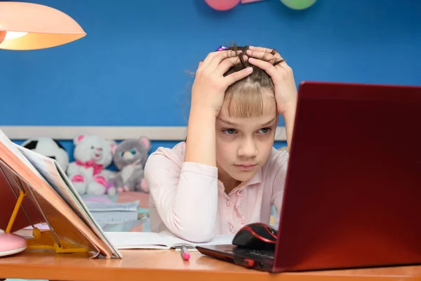 女の子は自宅でオンラインで勉強するという課題に直面した — ストック写真