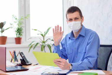 Uzaktan çalışan tıbbi maskeli bir ofis çalışanının portresi.