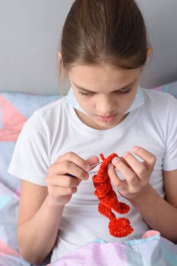 Karantinada bir kız örgü oyuncaklarıyla meşgul.