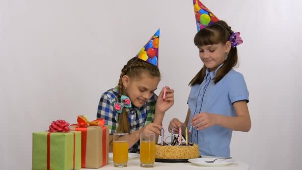 Duas meninas colocam velas em um bolo de aniversário — Vídeo de Stock