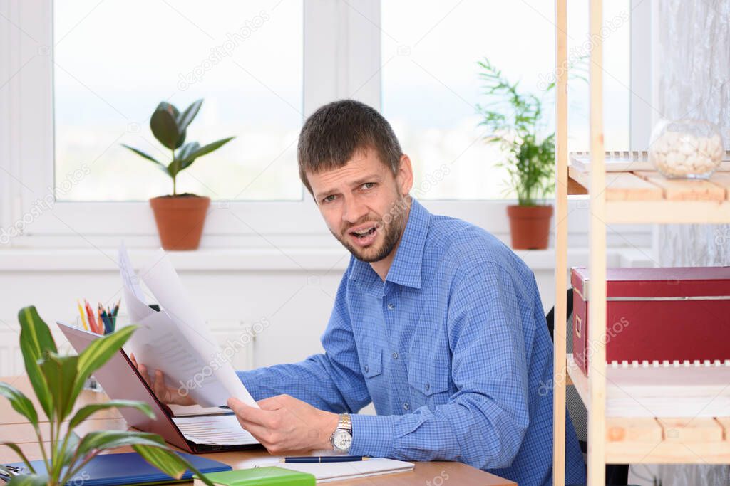 The office employee in a shocked state reads business papers and looked into the frame.