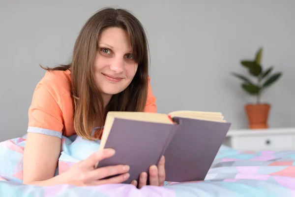 Das Mädchen Liest Ein Buch Und Blickt Lächelnd Den Rahmen — Stockfoto