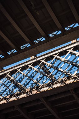 Manchester metrosundaki tarihi demiryolu köprülerinin altında karanlık ve kasvetli bir endüstriyel atmosfer var. Güneş ışınları yaz günü mavi gökyüzü.