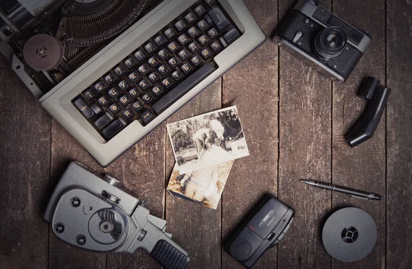 Still life with a typewriter, an old movie camera, a vintage camera on a textured wooden surface