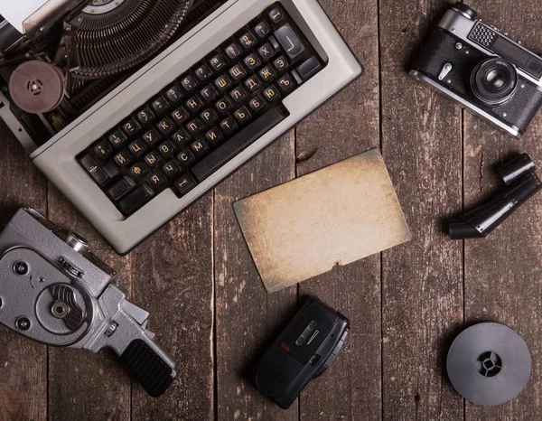 Still life with a typewriter, an old movie camera, a vintage camera on a textured wooden surface