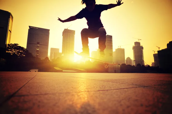Femme skateboard au lever du soleil ville — Photo