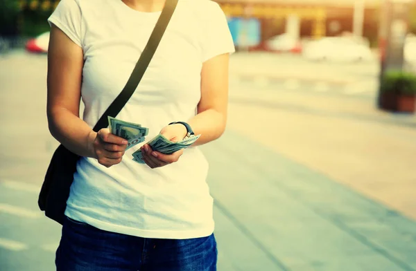 Jonge vrouw die dollarbiljetten telt — Stockfoto