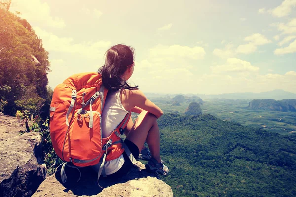 Frau mit Rucksack sitzt auf Berggipfel — Stockfoto