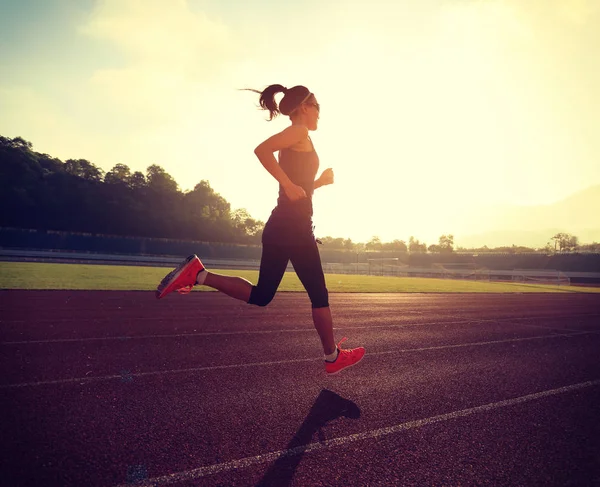 Mujer joven corriendo en pista de estadio — Foto de Stock