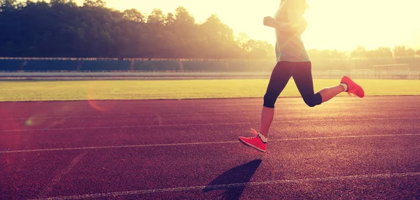 Jeune femme courant sur la piste du stade — Photo