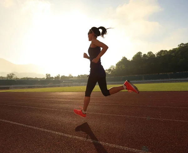 Mujer joven corriendo en pista de estadio — Foto de Stock