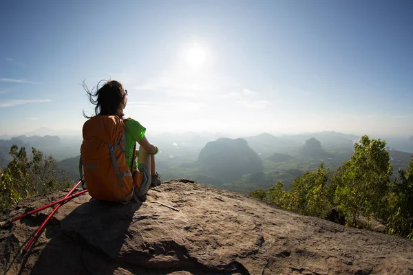 Mujer con mochila sentado en el pico de la montaña —  Fotos de Stock
