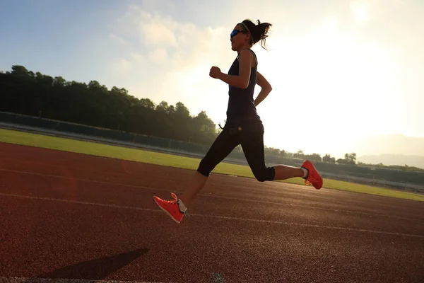 Young woman running on stadium track — Stock Photo, Image