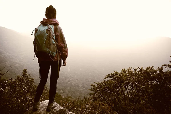 Vrouw met rugzak staande op de berg — Stockfoto