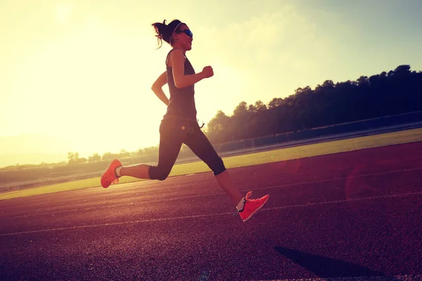 Young woman running on stadium track — Stock Photo, Image