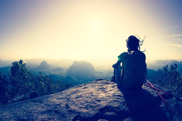 Mujer con mochila sentado en el pico de la montaña — Foto de Stock