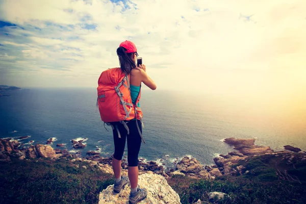 female hiker taking picture of sea