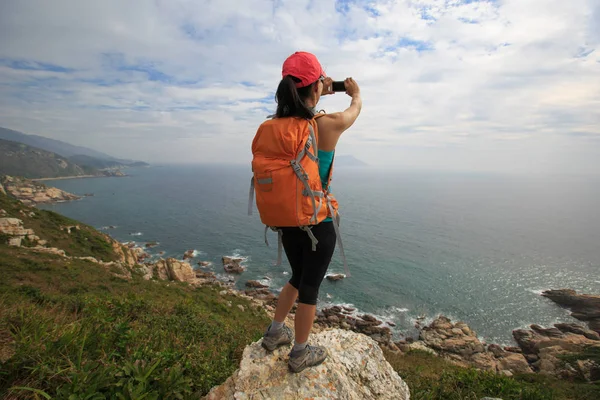 Senderista femenina tomando fotos del mar — Foto de Stock