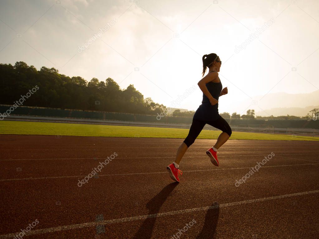 Young woman running on stadium track