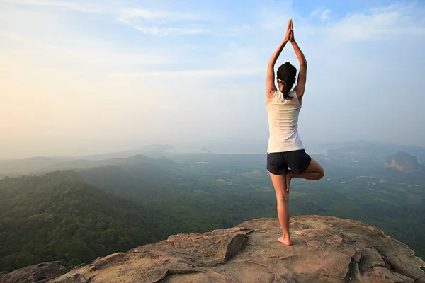 Mujer practicando yoga en el pico de la montaña —  Fotos de Stock