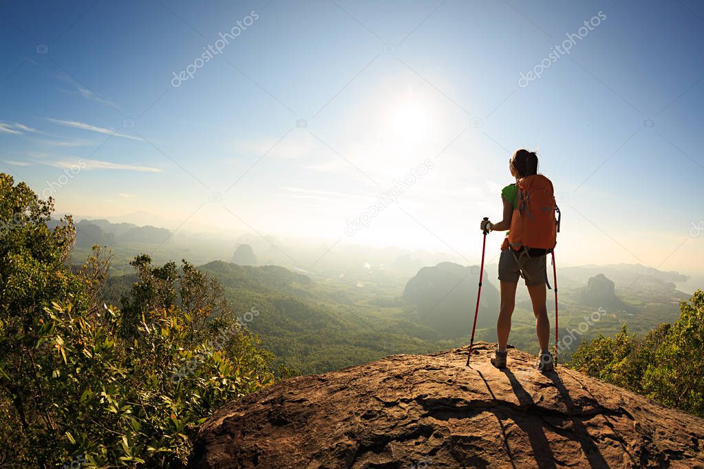 female backpacker standing on mountain peak