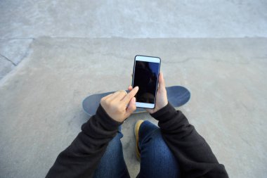 Genç kaykaycı Smartphone kullanarak