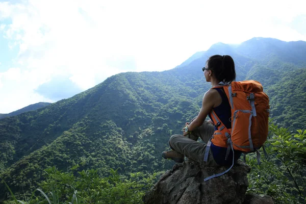 Mulher com mochila sentada no pico — Fotografia de Stock