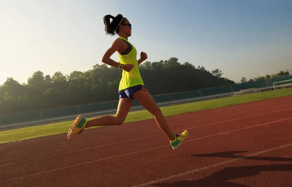 Mujer joven corriendo en pista de estadio — Foto de Stock