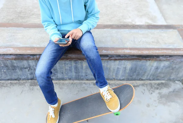 Young skateboarder using smartphone — Stock Photo, Image
