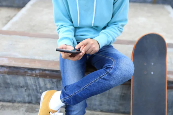 Giovane skateboarder utilizzando smartphone — Foto Stock